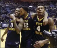  ?? RAYMOND THOMPSON — THE ASSOCIATED PRESS ?? West Virginia’sTarik Phillip (12) kisses guard Teyvon Myers (0) as they walk off the court with Daxter Miles Jr. (4) after beating Iowa State, Friday in Morgantown, W.Va.