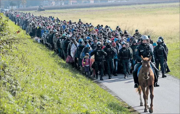  ?? SRDJAN ZIVULOVIC / REUTERS ?? La policía conduce a una columna de refugiados en Dobova, en el este de Eslovenia, cerca de la frontera con Croacia