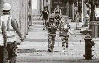  ?? Jon Shapley / Staff photograph­er ?? People wearing masks walk down Fannin Street on Wednesday. Face coverings and fabric masks will be mandatory in public beginning Monday, Harris County Judge Lina Hidalgo ordered.