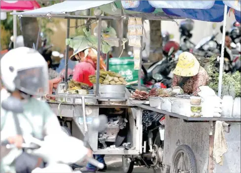  ?? HONG MENEA ?? A woman sells food outside a hospital in Phnom Penh in July.