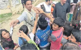  ??  ?? Having volunteere­d most of his life to improving the lives of Thai orphans, Sittisak Wongkasorn, seen here with Syrian refugee children, has always been passionate about helping those in need. ABOVE
Sittisak distributi­ng sweets to Syrian refugee...