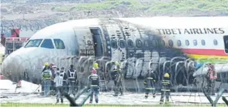  ?? / ST R I N G E R ?? Rescue workers attend to an Airbus A319 plane of Tibet Airlines, which caught fire after an aborted takeoff, at Chongqing Jiangbei Internatio­nal Airport in Chongqing, China.