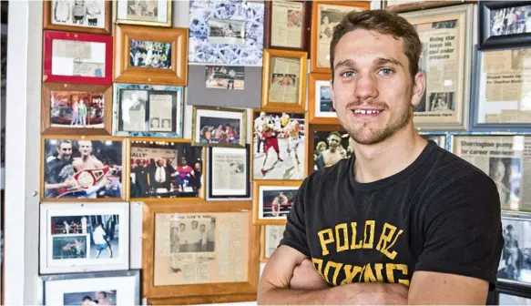  ??  ?? HISTORY BECKONS: Australian title contender Steve Spark admires Toowoomba boxing memorabili­a adorning the walls of TGW & Smithy’s Gym.