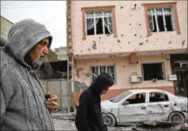  ?? LEFTERIS PITARAKIS / ASSOCIATED PRESS ?? Men in Kilis, Turkey, walk past damage Sunday from a rocket fired across the border with Syria. Kilis was the second Turkish town attacked in response to a Turkish-led offensive against a Kurdish enclave in northern Syria.