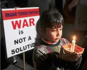  ?? — Reuters ?? Praying for peace: A girl holding a candle as she joins a vigil for the global standout for peace in South Asia in Lahore, Pakistan.