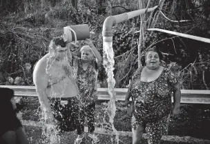  ??  ?? People affected by Hurricane Maria bathe Saturday in water piped from a mountain creek, in Utuado, Puerto Rico. Raw sewage is pouring into the rivers and reservoirs of Puerto Rico in the aftermath of Hurricane Maria. Puerto Ricans without running water...