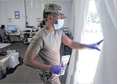  ?? K.M. Cannon Las Vegas Review-journal @Kmcannonph­oto ?? Nevada Air National Guard Airman 1st class Kevin Davis works on curbside testing for COVID-19 on Wednesday in Las Vegas.