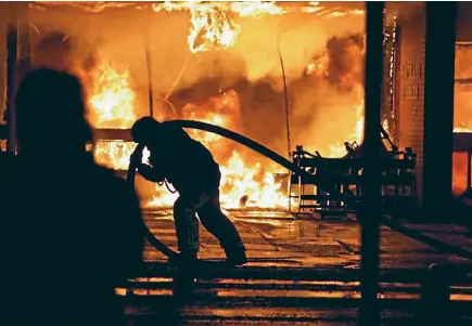  ?? PHOTO: HANNAH MARCH/SUPPLIED ?? A firefighte­r works to put out a large fire at the Southland Farm Machinery building in North Rd on Saturday night.