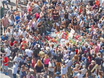  ?? AFP ?? People gather to leave candles, flowers, messages, stuffed toys and many different objects for the victims on Friday at the spot where Thursday’s van ploughed into the crowd on the Rambla boulevard in Barcelona. —