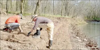  ?? Keith Bryant/The Weekly Vista ?? John Boonfield Esquire, left, helps Jesse Scarbrough lay down netting over freshly-sod native plants alongside Little Sugar Creek. The biodegrada­ble netting is made from coconut husks and will help stabilize the soil while plant roots develop,