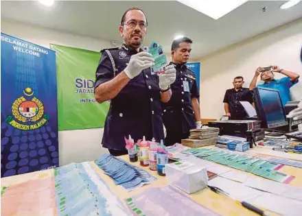  ?? PIC BY ASYRAF HAMZAH ?? Immigratio­n director-general Datuk Seri Mustafar Ali showing the seized items, at the Home Ministry Complex in Kuala Lumpur yesterday.