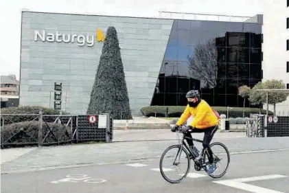  ??  ?? Un cicilista pasa por delante de la sede de la eléctrica Naturgy, en Madrid.