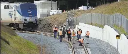  ?? ELAINE THOMPSON — THE ASSOCIATED PRESS ?? Workers inspect tracks Tuesday near the rear car of a crashed Amtrak train standing where the southbound tracks make a curve left in DuPont, Wash. Three men were killed when the Amtrak train careened off the overpass south of Seattle on Monday.