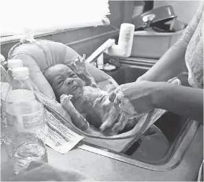  ?? TODD MCINTURF/AP ?? Porshe Loyd uses bottled water to wash her 3-week-old son, LeAndrew, at home in Flint, Mich, on Jan. 28, 2016.