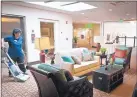 ??  ?? Yvonne Montoya vacuums a sitting area at MorningSta­r of Albuquerqu­e at Palomas NE. The assisted-living center welcomed its first residents Thursday.