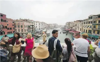  ?? LUCA BRUNO, AP ?? Tourists visit Rialto Bridge in Venice. Last summer, the number of tourist beds in the Italian city officially overtook the number of residents.