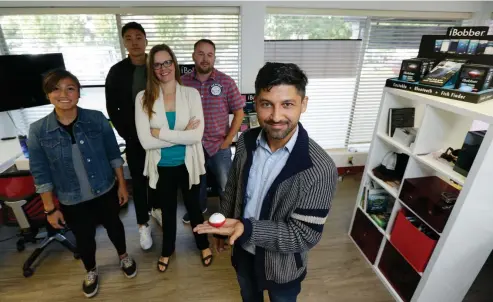  ?? Associated Press ?? above Alex Lebedev, right, owner of ReelSonar, holds one of his company’s products as he poses for a photo with co-workers Wednesday at ReelSonar’s headquarte­rs in Seattle. Texas and Florida are usually the biggest markets for ReelSonar’s fishing devices and apps, so the devastatio­n left by Hurricanes Harvey and Irma is expected to have an impact on sales, even though the company is located thousands of miles from the damage.