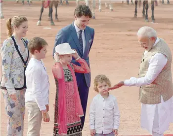  ?? — AFP ?? Narendra Modi touches the cheek of Hadrien Trudeau, the youngest son of Justin Trudeau and his wife Sophie Gregoire Trudeau, as their other children Ella-Grace and Xavier look on, while attending a ceremonial reception at the Presidenti­al Palace in New...