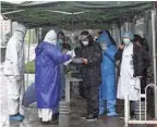  ?? CHINATOPIX VIA AP ?? Government workers wait Saturday for patients to arrive at a hospital designated to treat COVID-19 patients in Wuhan, China.