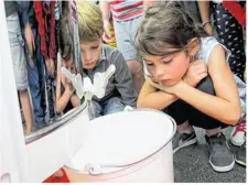  ??  ?? Les enfants du centre de loisirs ont attendu patiemment que le fil de miel tombe de la centrifuge­use dans le seau.