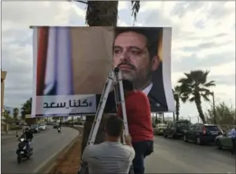  ?? HUSSEIN MALLA - THE ASSOCIATED PRESS ?? Workers hang a poster of outgoing Prime Minister Saad Hariri with Arabic words that read, “We are all Saad,” on a seaside street in Beirut, Lebanon, Nov. 9. Hezbollah has called on Saudi Arabia to stay out of Lebanese affairs, saying the resignatio­n of...