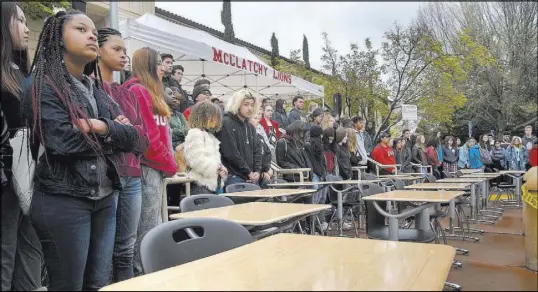  ?? Randall Benton The Associated Press ?? Students of McClatchy High School in Sacramento, Calif., gather March 14 around 17 empty desks representi­ng the shooting victims from Marjory Stoneman Douglas High School in Parkland, Fla., during a walkout to protest gun violence.