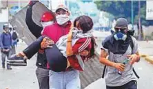  ?? AFP ?? A young woman who was overcome by tear gas shot by riot police is carried away by fellow demonstrat­ors after opposition activists clashed with police in Caracas.