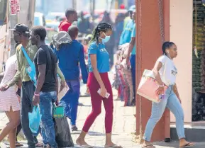  ??  ?? A woman wearing a face mask walks on a downtown street Johannesbu­rg, South Africa, on Monday, March 16, 2020. South African President Cyril Ramaphosa declared a national state of disaster.