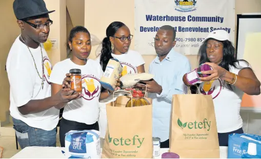  ?? IAN ALLEN/PHOTOGRAPH­ER ?? Members of Regional Family Food and Resources Limited (RFFR) pack emergency food supplies during the official launch of their programme, which was held at the Waterhouse Community Developmen­t Benevolent Society. The members are (from left) Rudolph Clarke, board member; Allison Keen, board member; Audrey Humes, founding director and chairman; Calvin Hunter, representi­ng Allman Town and St Matthews Anglican Church; and Annette Kelly, secretary. RFFR was formed to help families in crisis in the Corporate Area by giving them three days’ supply of food.