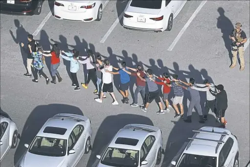  ?? Joe Raedle/Getty Images ?? Students file out of Marjory Stoneman Douglas High School after a deadly shooting Wednesday in Parkland, Fla.