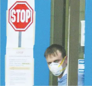  ?? POSTMEDIA NEWS FILES ?? A staff member at York Central hospital in Richmond Hill glances out the doors of the closed facility after fears the 2003 SARS outbreak was spreading further. At its peak, the outbreak caused people to avoid human contact, one epidemiolo­gy professor says,