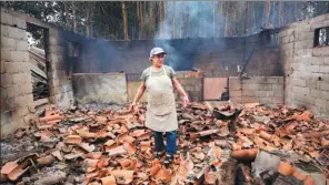  ?? SERGIO AZENHA/ASSOCIATED PRESS ?? A woman walks among the debris of the burnt shed where she raised chickens and pigs in a village in Portugal on Monday.