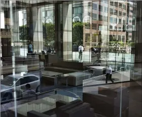  ?? RICHARD VOGEL — ASSOCIATED PRESS FILE ?? In this 2018 photo, downtown Los Angeles buildings and office workers are reflected in the front windows of a bank.