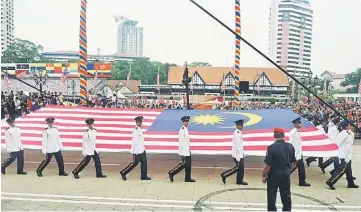  ??  ?? Independen­ce Day parade participan­ts with the Jalur Gemilang flag.