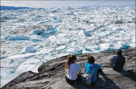  ?? SEAN GALLUP / GETTY IMAGES / TNS ?? Visitors look out onto free-floating ice jammed into the Ilulissat Icefjord during unseasonab­ly warm weather Tuesday near Ilulissat, Greenland. The Sahara heat wave that recently sent temperatur­es to record levels in parts of Europe is arriving in Greenland.