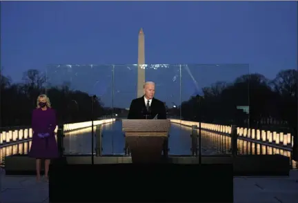  ?? ALEX BRANDON — ASSOCIATED PRESS ?? President-elect Joe Biden speaks during a COVID-19 memorial ceremony Tuesday evening in Washington, D.C., with the Reflecting Pool and Washington Monument behind him. At right is Biden’s wife, Jill.