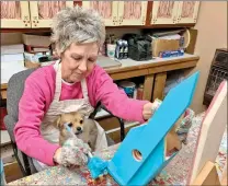  ?? ANDREA BRUNER/CONTRIBUTI­NG PHOTOGRAPH­ER ?? Marcia Milligan paints a birdhouse inside the shop she shares with her husband, Gary. Their puppy, Shortcake, finds her usual spot in Marcia’s lap. The Milligans have been crafting together for 40 years.