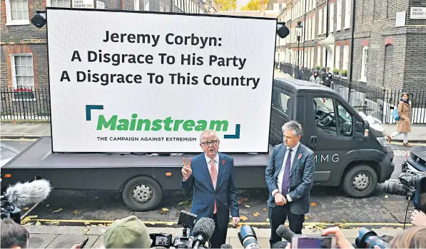  ??  ?? Ian Austin and John Woodcock unveil a campaign billboard calling on voters to shun Jeremy Corbyn’s Labour