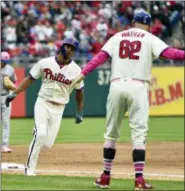  ?? DERIK HAMILTON — THE ASSOCIATED PRESS ?? Philadelph­ia Phillies’ Nick Williams, center, is congratula­ted by Dusty Wathan after hitting a three-run home run off New York Mets’ Paul Sewald during the sixth inning of a baseball game, Sunday in Philadelph­ia.