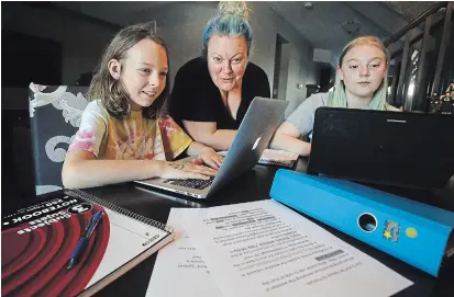  ?? CLIFFORD SKARSTEDT EXAMINER ?? Personal support worker DeeDee Burke assists her daughters Reina, 9, a Grade 4 student at King George Public School, and Rowena, 16, a Grade 11 Thomas A. Stewart Secondary School student, with their online learning on Thursday.