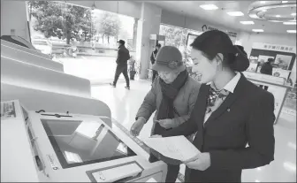  ?? XU BORAN / FOR CHINA DAILY ?? A bank branch manager helps a senior citizen to buy wealth management products using an automated self-service machine in Nantong, Jiangsu province, on Jan 3.