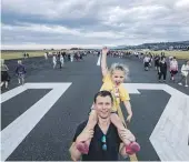  ?? ?? Air New Zealand pilot Joe Cottle and his daughter Alice Cottle, 3, walk past the landing designator during Nelson Airport’s walk the runway event on Saturday evening.