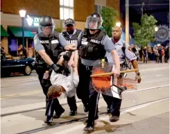  ?? — AFP ?? Policemen arrest a man as they try to clear a violent crowd in University City, St. Louis, on Saturday.