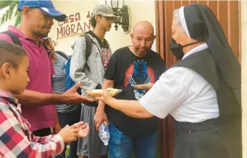  ?? ELLIOT SPAGAT/AP ?? Isabel Turcios, director of the Casa del Migrante migrant services center, delivers breakfasts to migrants June 1 in Piedras Negras, Mexico.