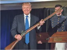  ?? RICHARD ELLIS, GETTY IMAGES ?? Then-candidate Donald Trump holds up a replica flintlock rifle given to him at The Citadel in South Carolina in February 2015.