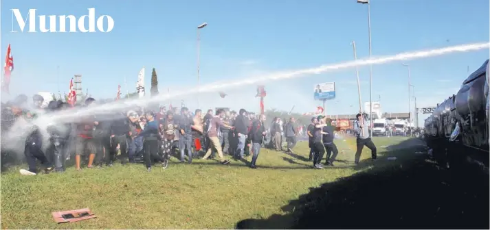  ?? FOTO: REUTERS ?? ►► Manifestan­tes que bloqueaban una ruta, en Buenos Aires, son alcanzados ayer por un chorro de agua lanzado por miembros de la Gendarmerí­a argentina.