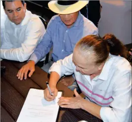  ?? PHOTO BY CESAR NEYOY/BAJO EL SOL ?? SAN LUIS DEVELOPER NIEVES RIEDEL SIGNS DOCUMENTS transferri­ng a lot to a nonprofit organizati­on and another group that will build a domestic violence shelter on the land in San Luis.