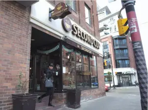  ?? CP PHOTO ?? A customer carries her coffee as she leave a Second Cup coffee retailer in Toronto on Dec. 5, 2016. Second Cup looking to convert some of its coffee shops into recreation­al cannabis dispensari­es and lounges.