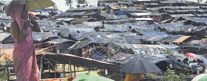  ??  ?? A Rohingya refugee shelters from the sun under an umbrella while looking on at the refugee camp of Balukhali, near the locality of Ukhia, Bangladesh.