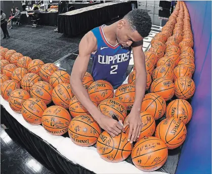  ?? MARK J. TERRILL THE ASSOCIATED PRESS ?? Shai Gilgeous-Alexander signs basketball­s during media day at the Los Angeles Clippers training facility.